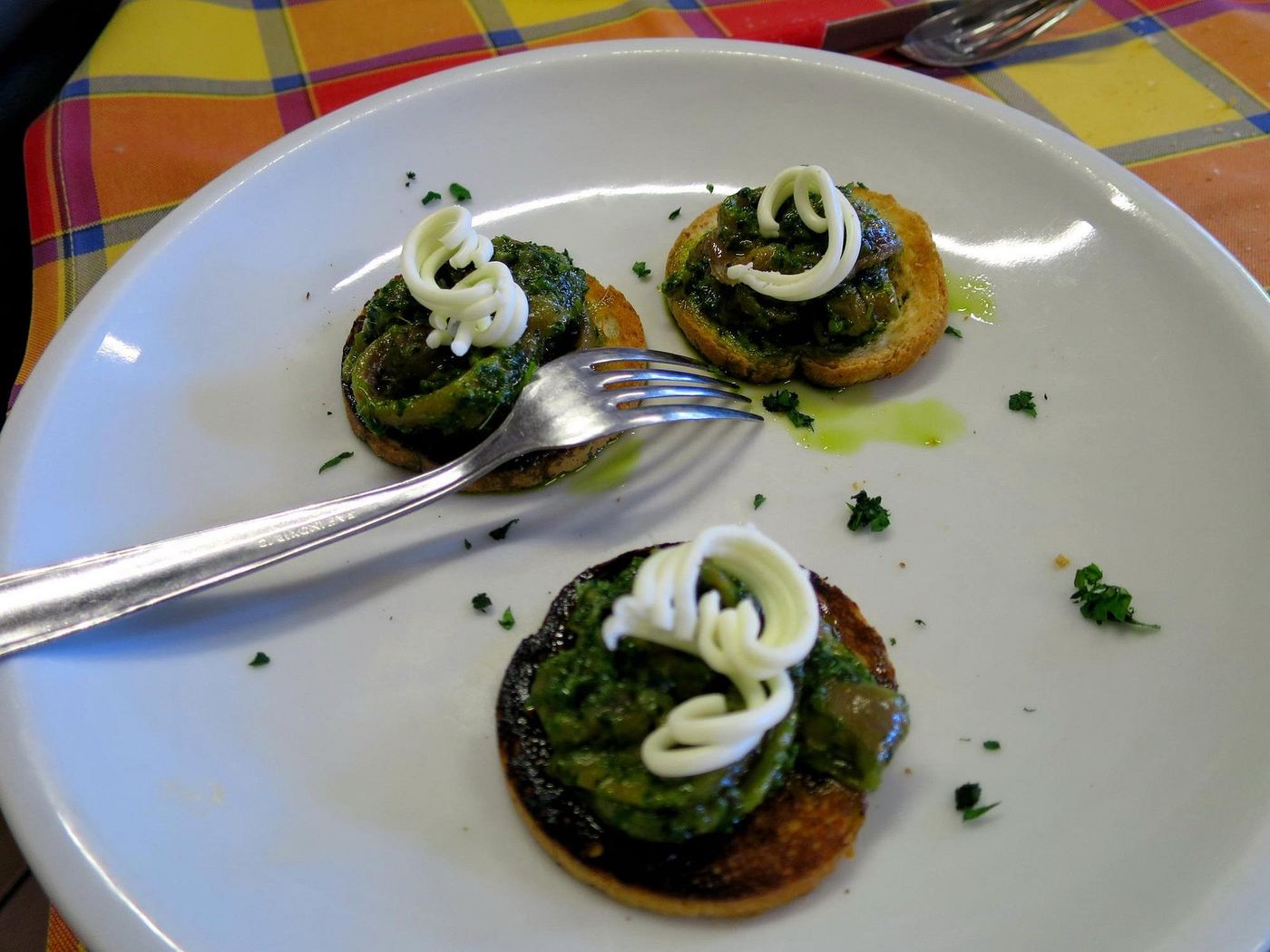 Crostini topped with green parsley sauce and a swirl of mayonnaise