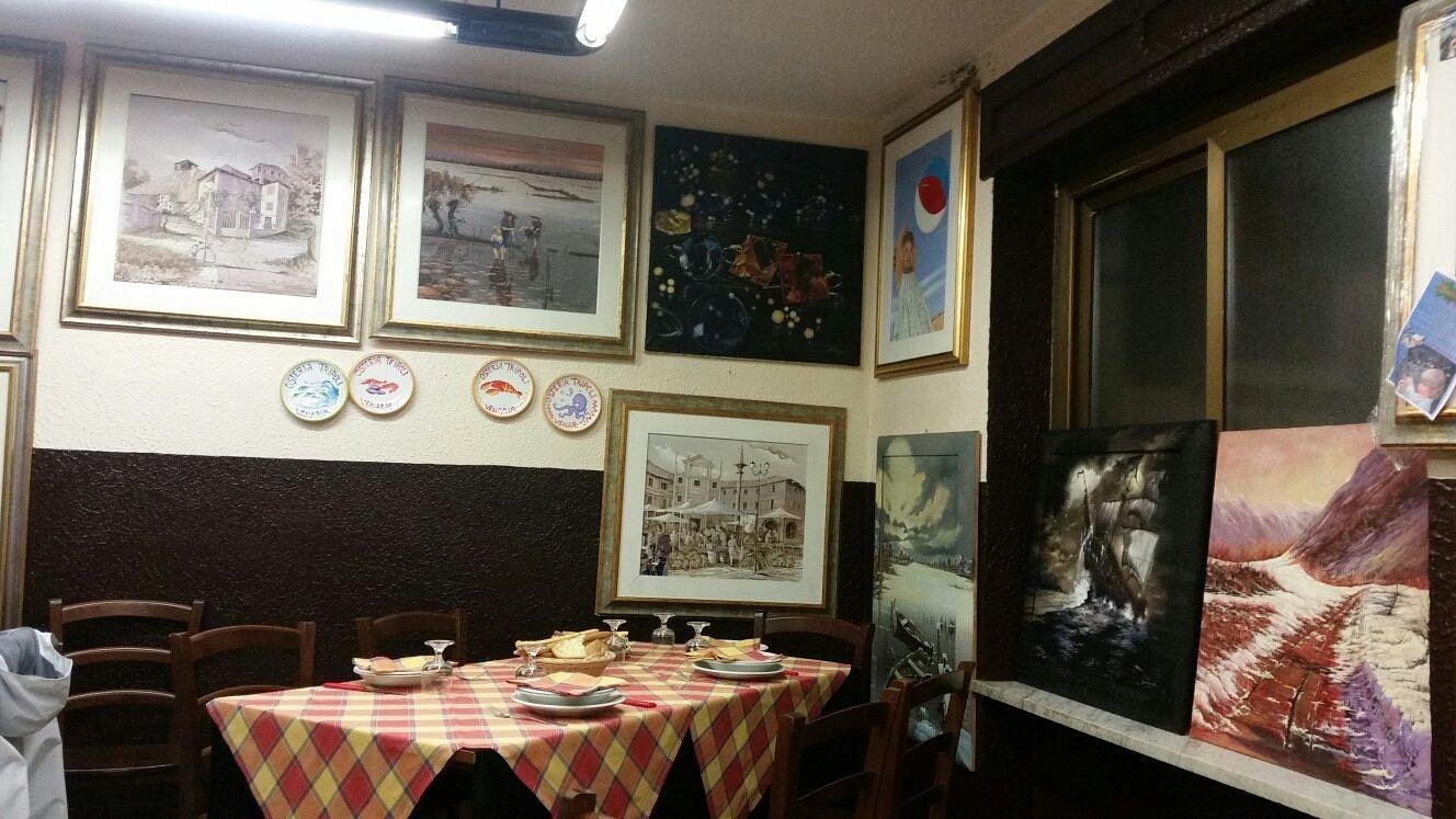 The dining room at Osteria Tripoli: tables with yellow and red checked tablecloths and walls covered in paintings